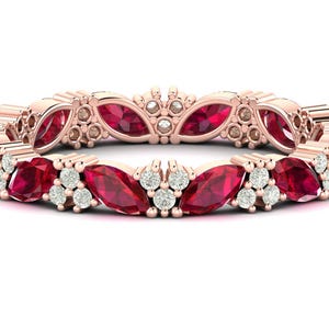 May include: Rose gold eternity ring with marquise-cut red gemstones and small round white gemstones. The ring's design features a repeating pattern of alternating red and white stones. A stunning piece of jewellery.