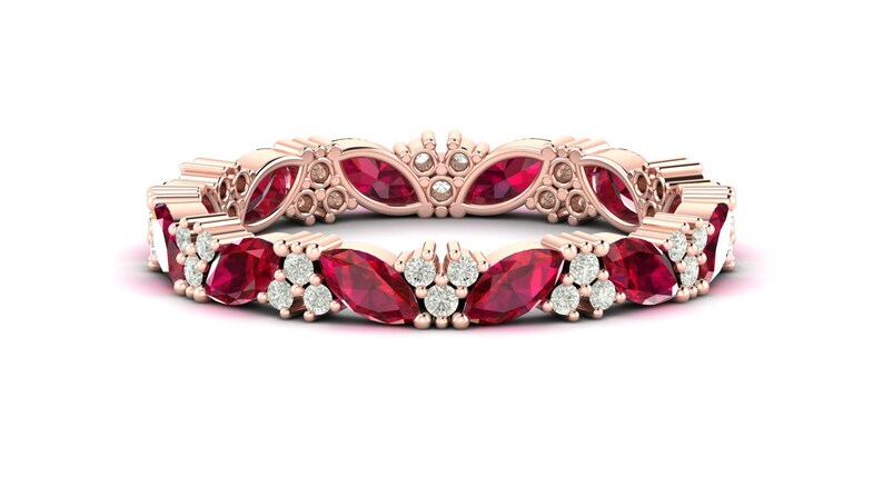 May include: Rose gold eternity ring with marquise-cut red gemstones and small round white gemstones. The ring's design features a repeating pattern of alternating red and white stones. A stunning piece of jewellery.