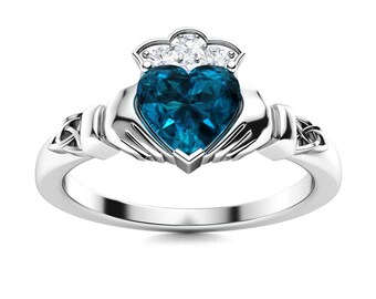 May include: A silver Celtic Claddagh ring with a blue topaz heart-shaped center stone and three smaller diamonds in the crown.