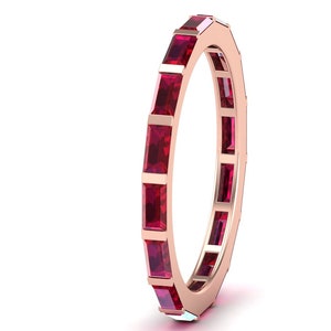 May include: A rose gold eternity band with a row of square-shaped ruby gemstones.