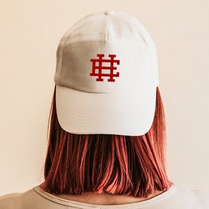 May include: A white baseball cap with a red embroidered hashtag symbol on the front.