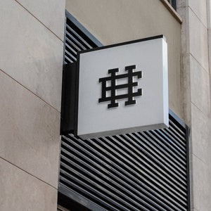May include: A white sign with a black hashtag symbol on a building.