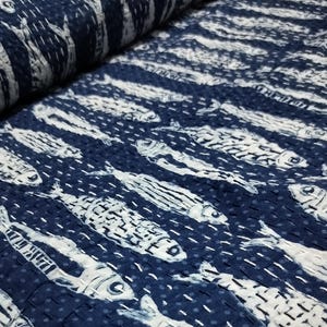 Peut inclure: Un tissu bleu et blanc avec un motif répétitif de poissons. Le tissu est matelassé et a une surface texturée.