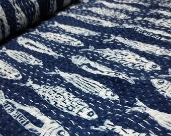 May include: A blue and white fabric with a repeating pattern of fish. The fabric is quilted and has a textured surface.