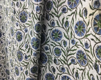 Könnte beinhalten: Weißer Stoff mit einem sich wiederholenden Muster aus blauen und grünen Blumen. Der Stoff hat eine leicht strukturierte Oberfläche.