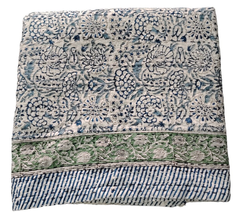 May include: A white cotton quilt with a blue and green floral pattern. The quilt has a green border with a floral design and a blue and white striped border.
