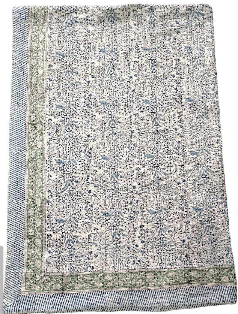 May include: A white cotton quilt with a blue and green floral pattern. The quilt has a border with a green and white striped pattern.