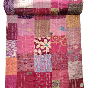 Puede incluir: Una colcha de retazos rosa y morada con una variedad de patrones florales y geométricos. La colcha está hecha de seda y está cosida a mano.