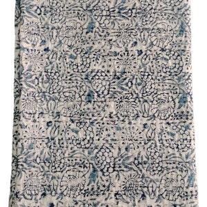 May include: A white cotton quilt with a blue and green floral pattern. The quilt has a border with a striped pattern.