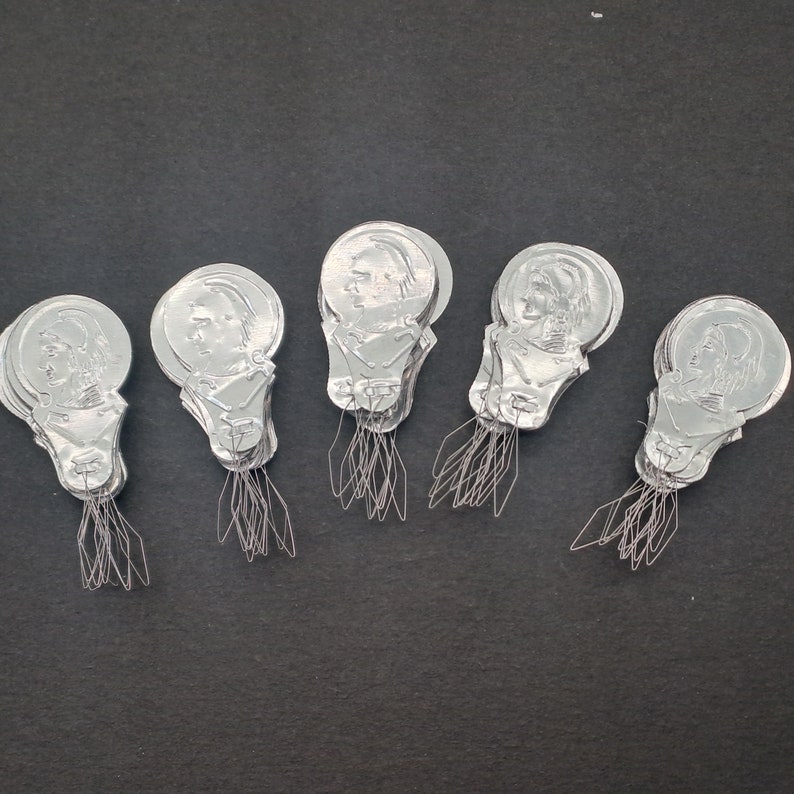 May include: Five silver threader tools with a person's face on each one. The tools are designed to help thread a needle.