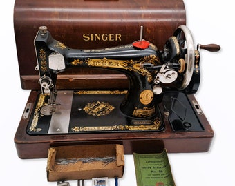 Singer 100 year old hand crank sewing machine, model 28K, with wooden case and some accessories