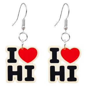 Puede incluir: Un par de pendientes colgantes con el texto "I ❤️ HI". Cada pendiente presenta un fondo blanco con letras negras y un corazón rojo. Los pendientes tienen ganchos plateados.