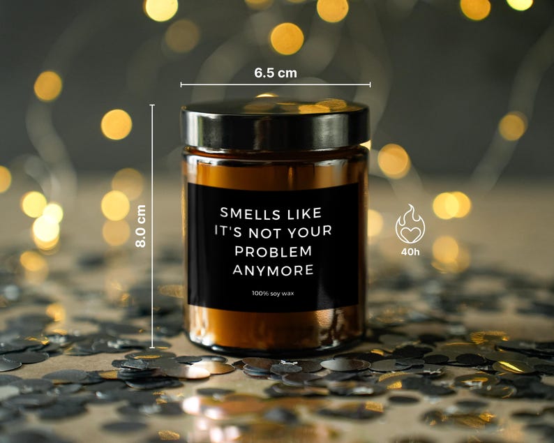 May include: A brown glass candle jar with a black label that reads "Smells Like It's Not Your Problem Anymore." The candle is 8.0 cm tall and 6.5 cm wide, with a burn time of 40 hours. Made with 100% soy wax.