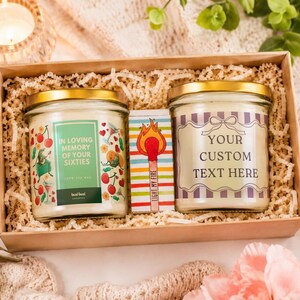 Op de afbeelding: Een geschenkdoos met twee glazen kaarsenpotten met gouden deksels en een klein luciferdoosje. Het linker etiket vermeldt IN LOVING MEMORY OF YOUR SIXTIES. Het rechter etiket vermeldt YOUR CUSTOM TEXT HERE. Het doosje toont een lucifer.