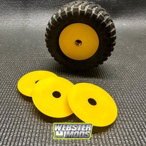 May include: Three yellow plastic wheel spacers for a remote control car. The spacers are designed to fit over the wheel hub and axle. The spacers are shown next to a black tire with a yellow wheel.