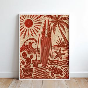 Könnte beinhalten: Ein rechteckiger Wandkunstdruck mit einer Illustration im Linolschnitt-Stil in Rot und Creme, die ein Stand-Up-Paddleboard, ein Paddel, eine Sonne, eine Palme, eine Welle, einen Seestern, eine Meeresschildkröte und einen Kaktus im Topf zeigt.
