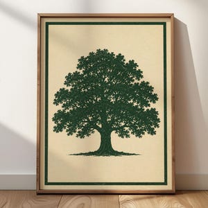 May include: A framed wall art print featuring a dark green illustration of a large, leafy oak tree centered on a light beige background. The artwork is enclosed within a thin dark green rectangular border and housed in a light brown wooden frame.