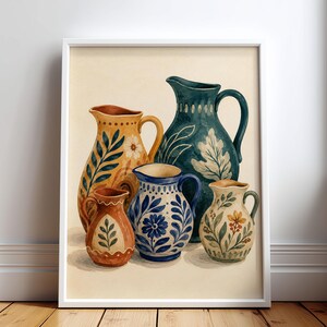 Könnte beinhalten: Ein gerahmter Kunstdruck mit einem Stillleben von fünf Keramikkrügen in verschiedenen Größen und Formen. Die Krüge sind mit bemalten botanischen Mustern in Blau-, Gelb-, Orange- und Grüntönen auf einem cremefarbenen Hintergrund verziert.