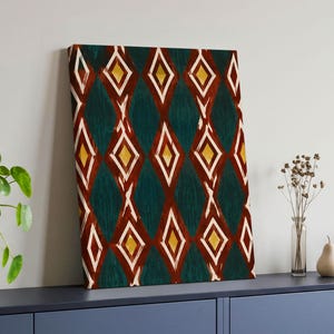 Könnte beinhalten: Ein rechteckiges Leinwandbild mit einem sich wiederholenden Rautenmuster. Das Design besteht aus dunkelblaugrünen, tiefroten und senfgelben Formen, die mit weißen Linien umrandet sind und ein geometrisches Motiv auf der gesamten Leinwand bilden.
