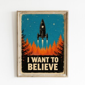 Pode incluir: Um cartaz emoldurado com um foguetão preto a descolar para um céu azul estrelado sobre uma floresta de pinheiros cor de laranja. O texto I WANT TO BELIEVE está impresso em letras maiúsculas cor de creme na parte inferior da imagem.