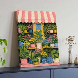 Könnte beinhalten: Ein rechteckiger Leinwanddruck mit einer farbenfrohen Illustration eines Blumenladens mit einer rosa-weiß gestreiften Markise. Die Szene zeigt mehrere Regale, die mit verschiedenen Topfpflanzen und Blumen in bunten Keramiktöpfen gefüllt sind.