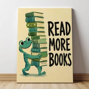 Könnte beinhalten: Ein rechteckiger Wandkunstdruck auf hellcremefarbenem Hintergrund mit einem grünen Frosch, der steht und einen hohen Stapel verschiedener grüner und blauer Bücher hält. Rechts neben dem Frosch und dem Bücherstapel steht der Text READ MORE BOOKS in Schwarz.