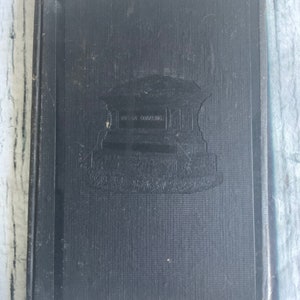 May include: Black hardcover book with a raised image of a building with the text "Boston Public Library" on the front cover.