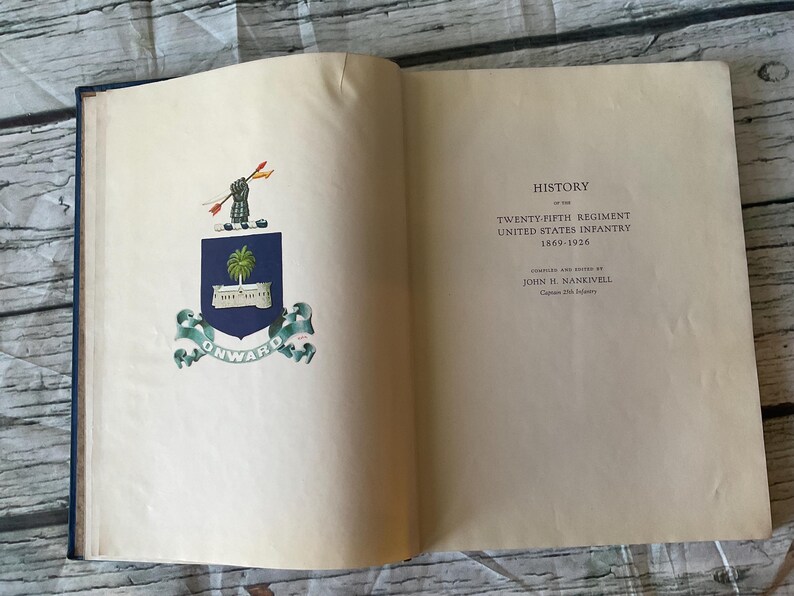 May include: Open book with the title page of a military history book. The left page features a crest with a palm tree and the word "ONWARD". The right page displays the title "HISTORY of the TWENTY-FIFTH REGIMENT UNITED STATES INFANTRY 1869-1926".