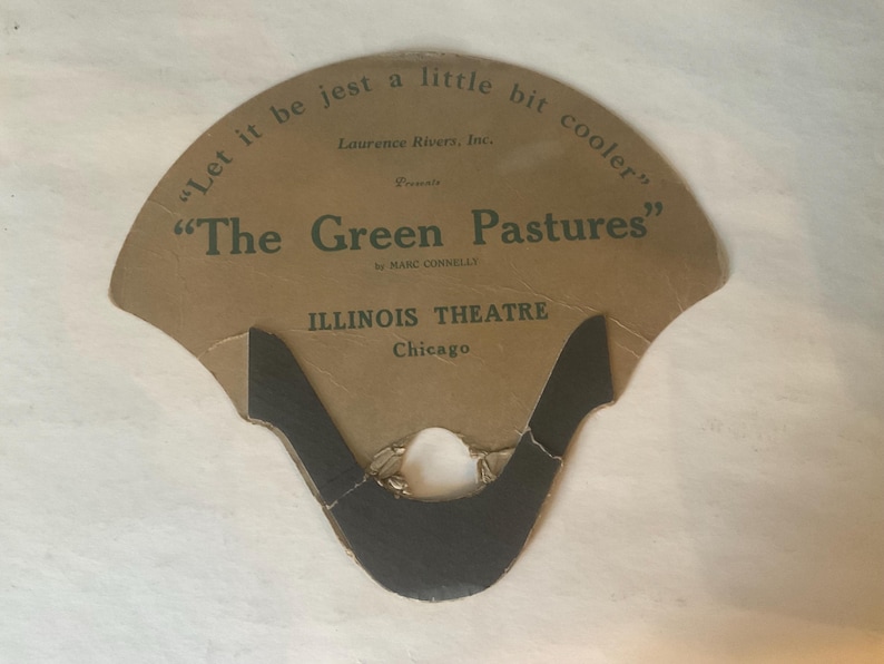 Op de afbeelding: Vintage waaier met een bruine papieren achtergrond. De waaier bevat de tekst "Let it be jest a little bit cooler" en "The Green Pastures" van Marc Connelly. Het Illinois Theatre in Chicago staat ook vermeld.