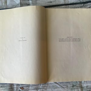 May include: An open book with aged, cream-colored pages. The left page has the text "Copyright, 1957 by JOHN H. MAXWELL". The right page is labeled "DEDICATED" with additional text. The book's spine is dark blue, and the pages are slightly yellowed.