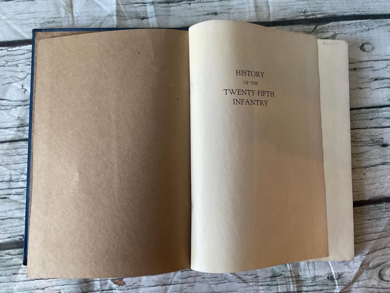 May include: Open book with a blue cover and aged pages. The text "HISTORY OF THE TWENTY-FIFTH INFANTRY" is printed in black on the right page. The left page is blank.