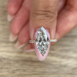 May include: A pear-shaped diamond engagement ring with a pave band set in rose gold.