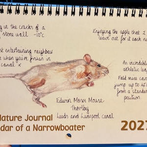 May include: A 2027 spiral-bound nature journal calendar featuring a coloured pencil illustration of a mouse in mid-leap. Handwritten text includes: Living in the cracks of a dry stone wall -10°C, Enjoying the apple that I leave out for it each night, An incredibly athletic leaper! Field mice can jump up to 45cm from a standing position. Edwin Moses Mouse, Thornby, Leeds and Liverpool canal. The Nature Journal Calendar of a Narrowboater.