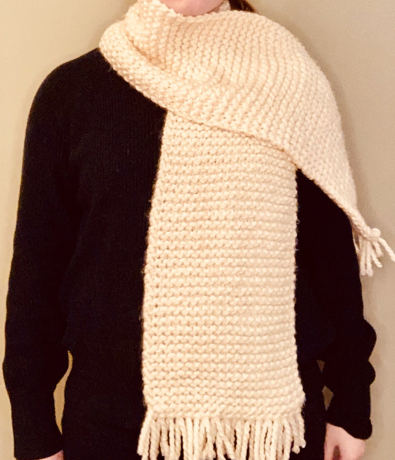 Ultra cozy hand-knit chunky cream colored scarf on model with black sweater.