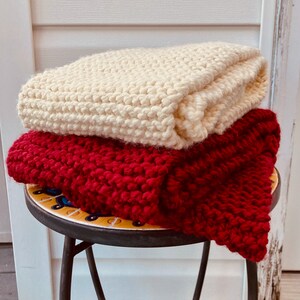 Hand-Knit Chunky Red and Cream Colored scarves against rustic wood background.