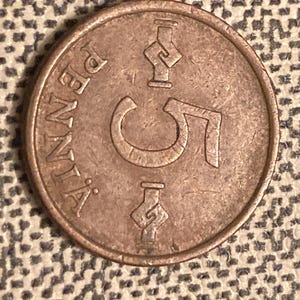 May include: A copper-colored coin with the number "5" and the word "PENNSYLVANIA" inscribed around the edge.