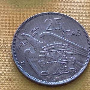 以下が含まれることがあります： 25 PTASと刻まれたスペインの銀貨。紋章の鷲と盾が描かれている。