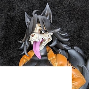 May include: A collectible figurine of an anthropomorphic wolf character with a skull mask and long tongue, wearing an orange jumpsuit. The figure stands on a circular base with a television set, a metal fence, and a ball and chain accessory.