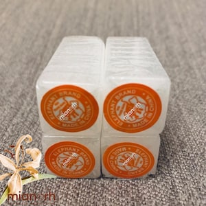 Puede incluir: Cuatro bloques rectangulares blancos apilados en forma cuadrada. Cada bloque tiene una pegatina circular naranja con el texto "ELEPHANT BRAND MADE IN CHINA" y el nombre "mianerh". Los bloques están sobre una superficie gris.