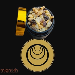 Puede incluir: Un recipiente negro lleno de trozos de resina variados, con una tapa dorada al lado. El recipiente está sobre una superficie negra, con un logotipo dorado y el texto "mianorh" y "waken the magic within" en la parte inferior.