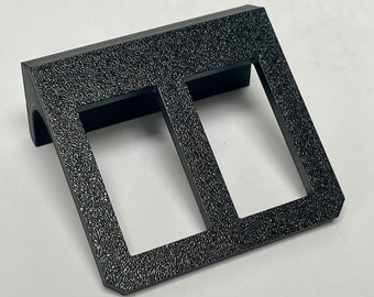 May include: Black plastic double toggle switch plate with a textured surface.