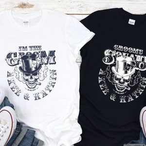 May include: Two t-shirts with a skull and top hat design. The white t-shirt says "I'm the Groom Alex & Katrin". The black t-shirt says "Groom's Squad Alex & Katrin".