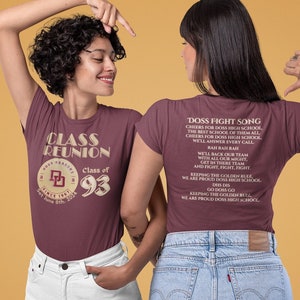 May include: Burgundy t-shirt with a vintage-style design featuring the text "Class Reunion" and the year "93". The back of the shirt features the text "Doss Fight Song" and lyrics about the school.