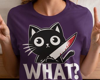 May include: Purple t-shirt with a black cat holding a bloody knife and the text "WHAT?"