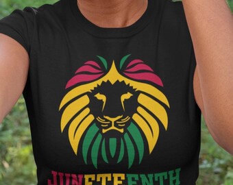Può includere: T-shirt nera con un disegno di leone nei colori rosso, giallo e verde, con la scritta "Juneteenth is My Independence Day". Il design è una vibrante celebrazione della libertà e del patrimonio.