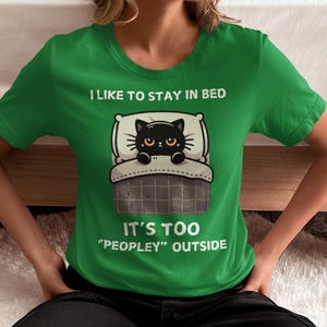 May include: Green t-shirt with a black cat in bed and the text "I like to stay in bed. It's too "peopley" outside."