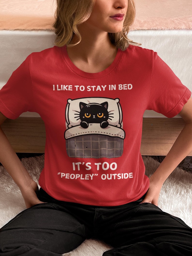 May include: Red t-shirt with a black cat in bed and the text "I like to stay in bed. It's too "peopley" outside."