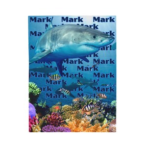 Può includere: Immagine digitale di un grande squalo bianco sopra una colorata barriera corallina. Lo sfondo è blu con la parola "Mark" ripetuta. La barriera corallina è colorata e vari pesci nuotano intorno. Tema marino.