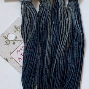 Peut inclure: Quatre écheveaux de fil à broder dans des tons de bleu et de gris. Le fil est disposé en pile verticale, la nuance la plus foncée en bas et la nuance la plus claire en haut.