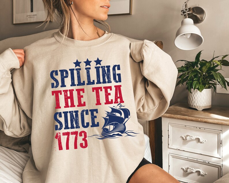 May include: A beige sweatshirt with a blue and red graphic print that says "Spilling the Tea Since 1773" with a ship illustration.